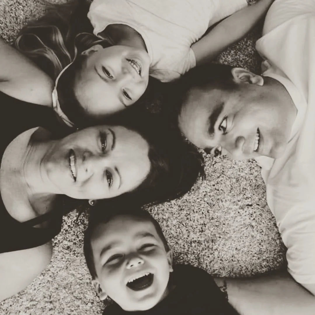 Emile and Bianca Smit, founders of Love Local, lying on a carpet with their two smiling children, captured in a joyful, family-centred moment.
